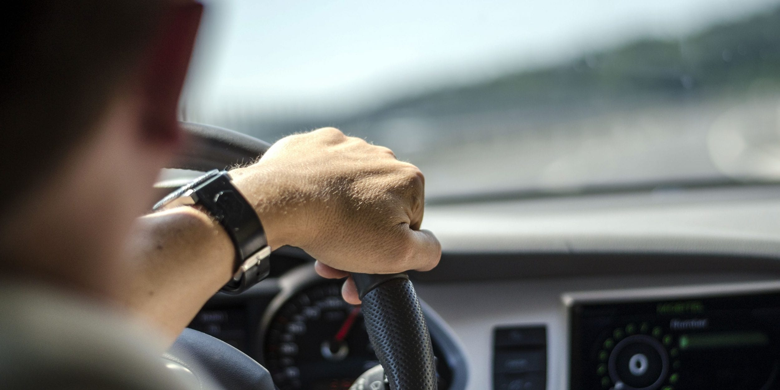 Man driving car with one hand on wheel
